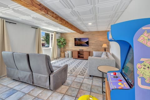 Enjoy endless fun in the downstairs game room featuring a pool table, Pac-Man and Fast & Furious arcade games, power recliners, and a smart TV for family entertainment.