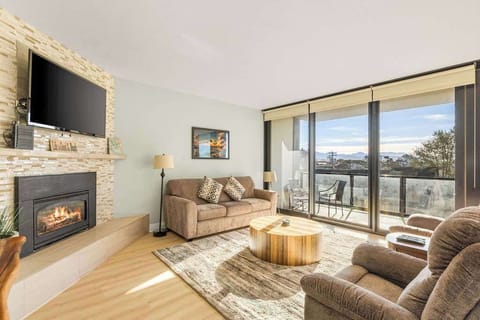 Bright, cozy living room with fireplace, balcony, and mountain views—perfect for relaxing after a day of adventure.
