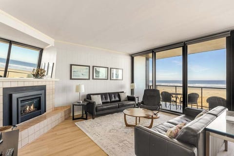 Stunning oceanview living room with cozy fireplace, floor-to-ceiling windows, and private balcony overlooking the beach.
