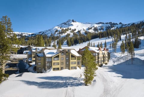 Embrace the cozy charm of snow-laden condos nestled against the majestic winter landscape, inviting adventure at your doorstep.