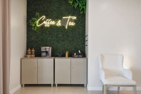 Charming coffee & tea station with neon glow, lush greenery, and cozy seating!