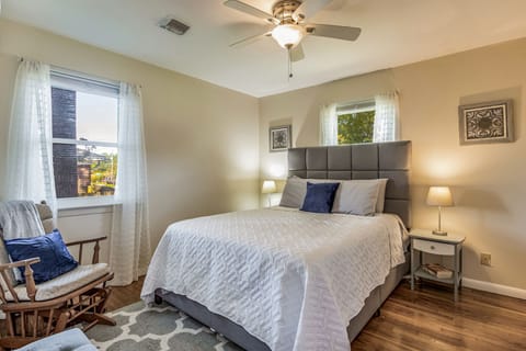 Queen bedroom with ample lighting, a rocking chair, and closet space.