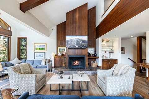 Spacious and beautifully designed living area featuring vaulted wood-beam ceilings, a grand fireplace, and plush seating. Perfect for relaxing after a day of mountain adventures.