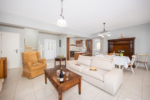 Open-plan living room with sofa, dining area, kitchen, ornamental fireplace, A/C, WiFi internet, and satellite TV