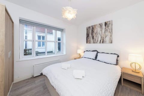 “Modern double room with fresh towels, bedside lamps, wardrobe, and a bright window view — perfect for tourists and professionals seeking comfort in central Reading.”