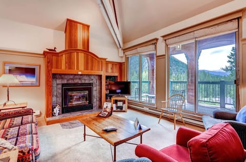 Bright, cozy living room with a fireplace and forest views.