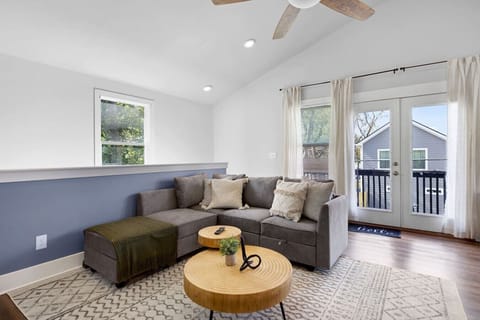 Spacious living room with sectional seating, large windows, and balcony access for fresh air 🌳🛋️🌞