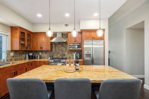 The modern kitchen boasts a spacious island with bar stools.  It’s equipped with a Nespresso machine, air fryer, blender, electric kettle, and a full set of cooking utensils, offering both style and functionality for any culinary needs.