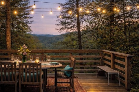 Twinkle-lit deck with forested mountain views—al fresco dining magic