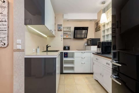 A modern kitchen with white cabinets, black appliances, and a light wood countertop. The space is well-organized, with open shelving for easy access to cooking essentials.