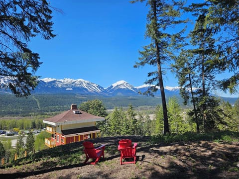 Relax in vibrant red chairs, soaking in breathtaking mountain vistas under a clear blue sky.