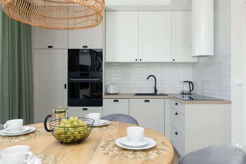 A minimalist kitchen area with white cabinets, a marble-style countertop, and modern appliances, including a built-in oven and sink.