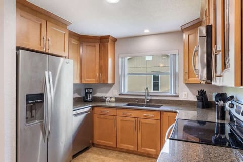 {KITCHEN} The open kitchen, seamlessly connecting to the living and dining areas, includes a spacious island, French door fridge, stove/oven, dishwasher, coffee maker, and all the essentials for cooking and enjoying meals.