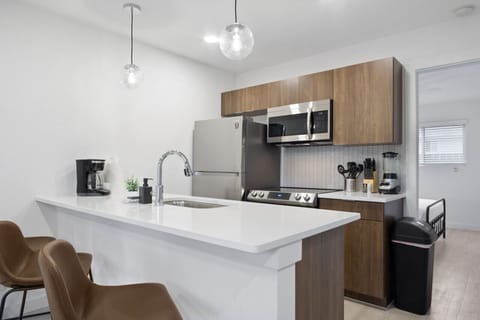 Prepare meals in this modern, fully-equipped kitchen featuring stainless steel appliances and a spacious island with bar seating. The open layout makes it easy to cook and entertain, ensuring a delightful culinary experience during your stay.