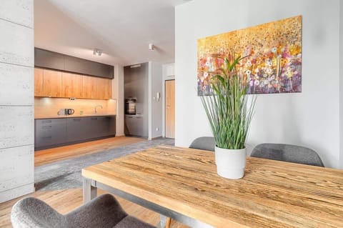 Dining area with wooden table, grey seating, and decorative vase with green plant.