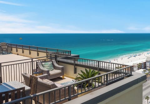Breathtaking beachfront balcony with wicker seating overlooking turquoise waters and pristine white sand—your perfect spot to sip morning coffee or unwind as parasails drift by.