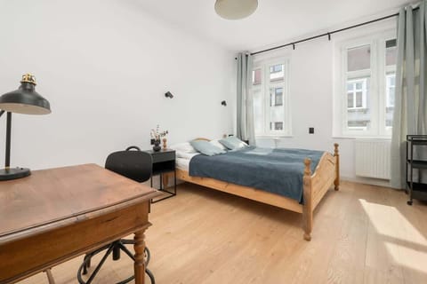 Bright bedroom with wooden floors, double bed and a window allowing natural daylight to fill the space.