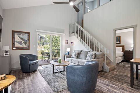 Bright living area showcasing open sight, a staircase to the upper level, and direct access to a private outdoor balcony, creating a welcoming and functional gathering space.