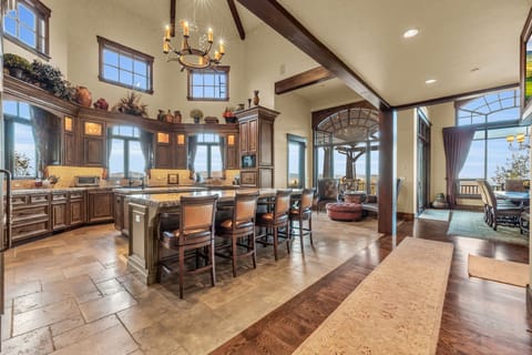 Gourmet kitchen with stone counters and dining room fitted with chandelier.