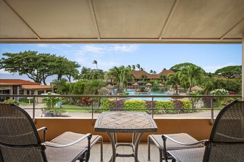Scenic views of lush tropical gardens and sparkling pool define the property's tranquil setting, framed by mature palms and verdant landscaping under blue skies.