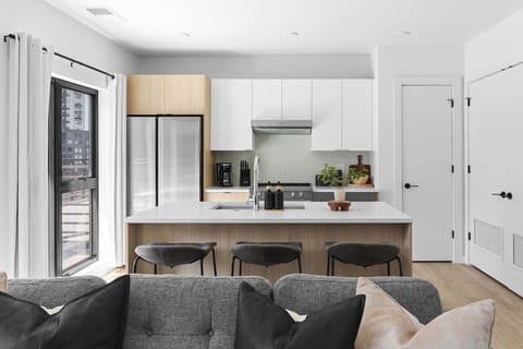 Fully equipped kitchen with high-end appliances and finishes, plus seating for three at the counter.