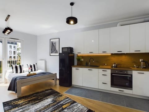 A bright and modern living space combining a sitting area with a gray sofa, TV, and dining table, seamlessly connected to the kitchen.