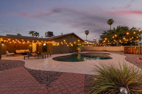 Gorgeous private backyard featuring a private pool, sun loungers, shaded patio with outdoor seating, and yard games like corn hole and giant jenga.