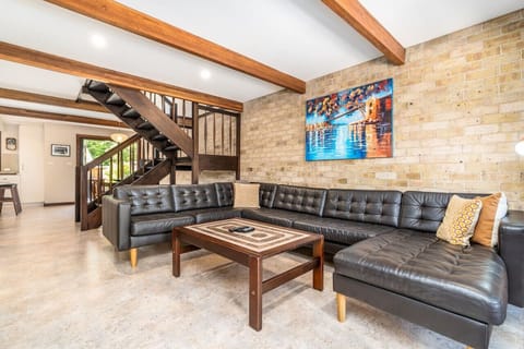 Spacious lounge room furnished with a large leather lounge and TV.