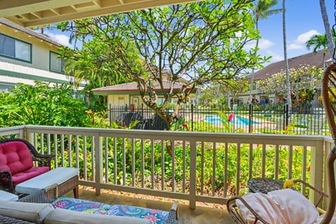 A bright tropical view from your private terrace overlooks lush gardens and a sparkling pool, framed by swaying palms and vibrant greenery—your perfect Hawaiian escape.