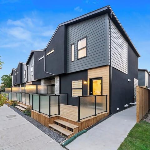 Modern townhouse with sleek black exterior, frosted glass & deck