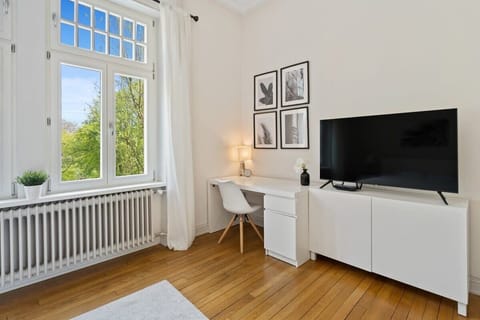 Cozy bedroom with a work desk, flat-screen TV, and large windows for a relaxing and productive stay.