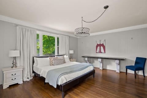 Spacious and serene bedroom featuring a king bed, large windows with leafy views