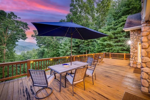 Main floor deck with large dining table, umbrella, rocking chairs, and grill.