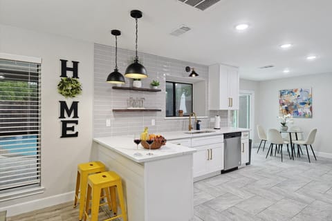 A bright and modern kitchen with sleek finishes, stylish pendant lighting, and a cozy breakfast bar. The open layout flows into the dining area, creating the perfect space for cooking, dining, and entertaining.