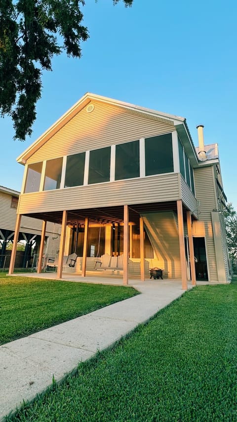 Modern elevated lake house with a spacious porch and open lawn.