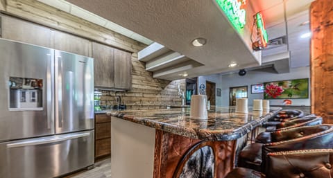 Downstairs game room bar area with refigerator