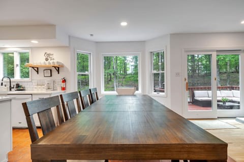 A grand dining table, perfect for a large family or a group of friends, awaits you in this luxurious space. The expansive windows frame the beautiful scenery outside.