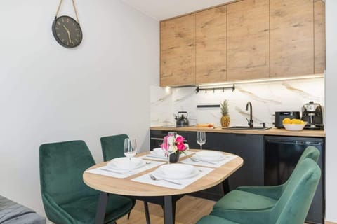 A round wooden dining table surrounded by soft chairs, perfect for meals or friendly gatherings.