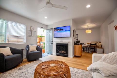 Charming and cozy living room featuring a fireplace, smart TV and large couch.