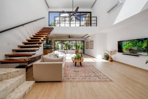 The villa boasts a huge, open-concept living room featuring a large, comfortable couch, a TV for entertainment, and a spacious dining area perfect for shared meals.