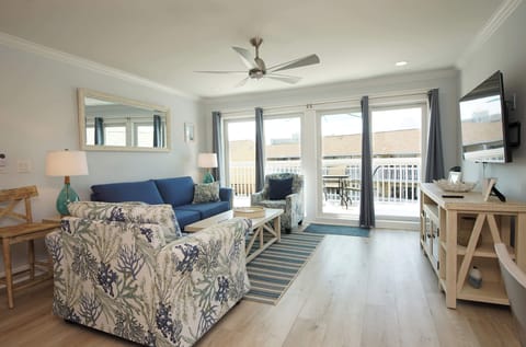 Relax in your coastal-inspired living room with ocean-themed décor, comfortable seating, and private balcony access.