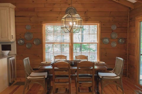 The dining area is well-lit by large windows that frame beautiful views of the surrounding nature.