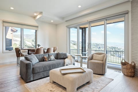 Sun-filled living room featuring a comfortable sectional sofa, stylish furnishings, and large windows with scenic views.