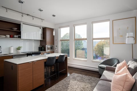 Welcome to your bright urban retreat! A beautifully integrated space featuring a bright kitchen and a cozy living area with expansive windows.