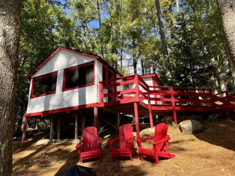 Nestled deep in the woods, this charming white and red cabin offers rustic tranquility with a touch of classic charm
