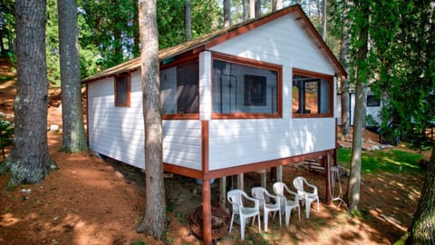 Nestled deep in the woods, this charming white and red cabin offers rustic tranquility with a touch of classic charm