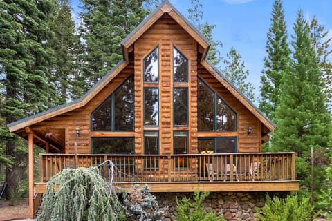 Charming log cabin nestled in the pines, featuring soaring A-frame windows, a spacious front deck, and rustic mountain appeal — perfect for a peaceful Lake Almanor getaway.