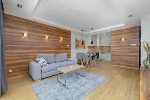 Modern living room with gray couch, wooden accent wall, and warm lighting.