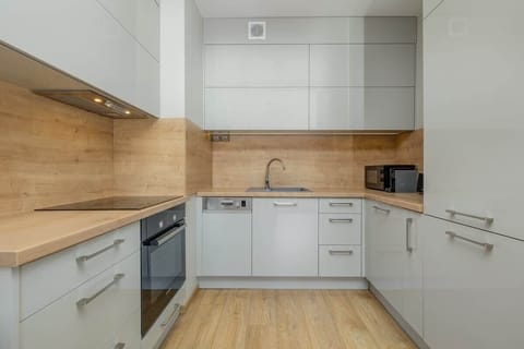 Contemporary kitchen with white cabinets, wooden backsplash, and built-in appliances.