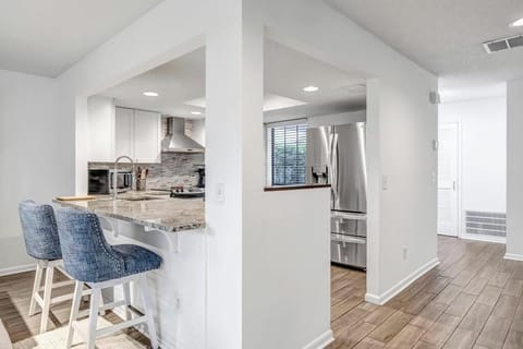 - Grab a snack or morning coffee at the granite breakfast bar with comfy blue barstools
- Modern stainless steel appliances and subway tile make cooking a treat
- Pass through kitchen design is perfect for easy hosting